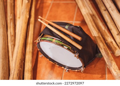 Two drumsticks on an Easter drum, resting on the ground next to wooden logs