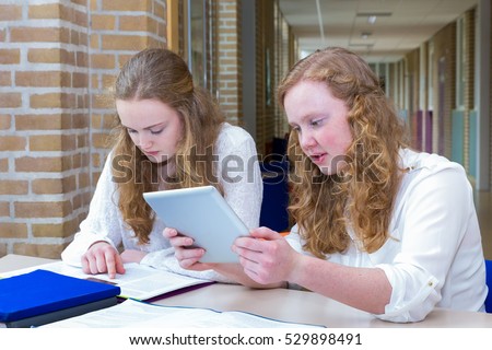 Two dutch teenage girls studying in corridor of high school