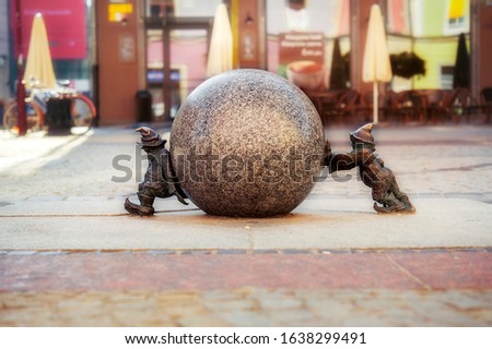 Two dwarfs pushing granite ball in Wroclaw, Poland. One of famous sculptures of dwarfs in Wroclaw, Breslau in past, symbols of polish city. travel destination. Tourism attraction