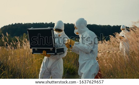 Two ecology experts eamining polluted water sample in test tube working on radioactive swamp danger area in countryside.