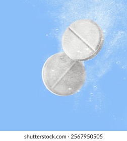 Two effervescent tablets fizz and dissolve on a bright blue background, creating a dynamic visual effect with air bubbles.