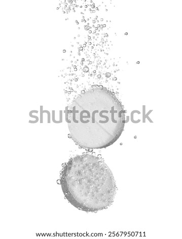 Two effervescent tablets fizz and dissolve on a white background, creating a dynamic visual effect with air bubbles.