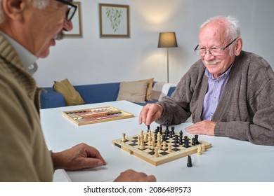 Two elderly men playing chess together at the table during leisure time in nursing home - Powered by Shutterstock