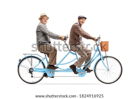 Two elderly men riding a blue tandem bicycle and smiling at camera isolated on white background