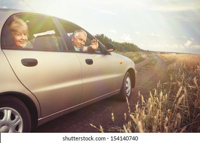 Two Elderly People In Car In Field