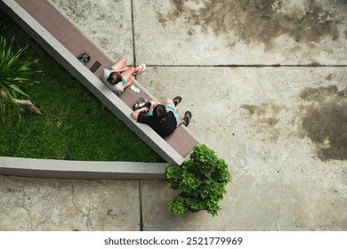Two elderly people are sitting and sharing stories on a park bench in the morning. A social interaction of modern urban residents in Jakarta, Indonesia.