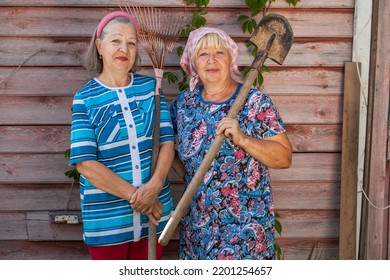 Two Elderly Women With A Garden Rake And A Shovel