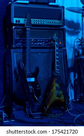 Two Electric Guitars Backstage At A Rock Concert Leaning Up Against Am Electronic Music Deck With The Amplifiers, Mixers And Equalizers