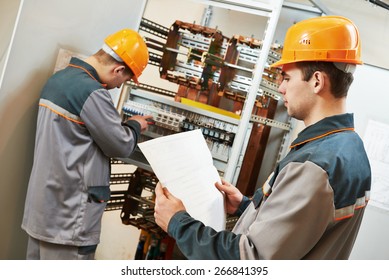 two electrician builder engineer works with electric cable wiring of fuse switch box