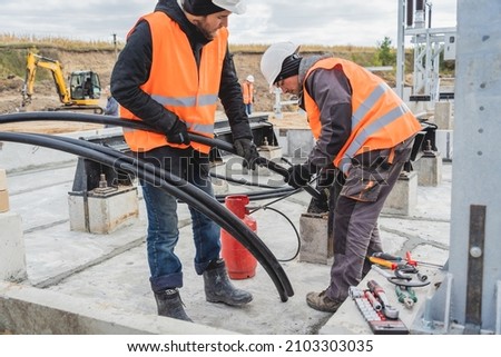 Two electrician builder workers installing high-voltage cable