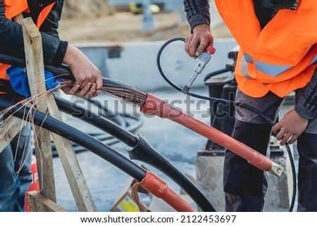 Two electrician builder workers installing high-voltage cable