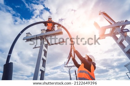 Two electrician builder workers installing high-voltage cable
