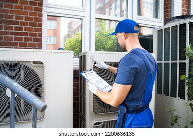 Two Electricians Men Wearing Safety Jackets Checking Air Conditioning Unit On Building Rooftop - Shutterstock ID 2200636135