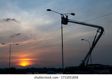 Two Electricians Repairing A Broken Street Light