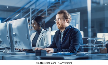 Two Electronics Development Engineers Working on Computers. Team of Professionals Use CAD Software for the Modern Industrial Engineering Design. In the Background Specialist Using Digital Whiteboard - Shutterstock ID 1699780621