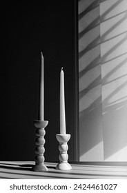 Two elegant bubble taper candle holders with taper candles in side blind lights on dark background. Interior design. Black and white