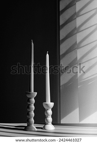 Two elegant bubble taper candle holders with taper candles in side blind lights on dark background. Interior design. Black and white