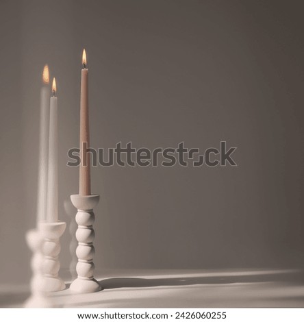 Two elegant bubble taper candle holders with burning taper candles on a neutral. Interior design.