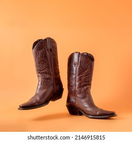 Two elegant classic cowboy boots on an orange clay background. Ranger cowboy concept on a ranch in america usa texas.