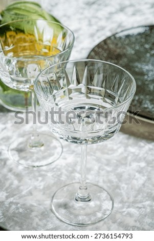 Two elegant crystal glasses sit, one filled with golden liquid, inviting a toast.