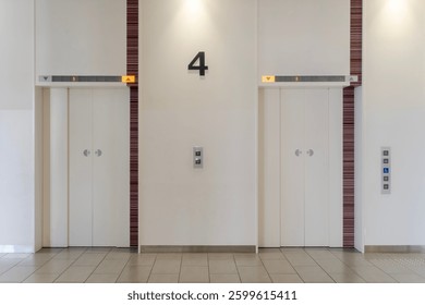 Two elevator doors stand side by side on the fourth floor of a modern building, with illuminated floor indicators above and sleek, minimalistic design emphasizing functionality and cleanliness.