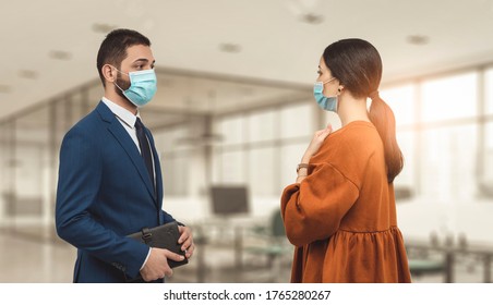 Two Employee Standing In Social Distance Wearing Face Mask Looking At Each Other And Talking In The Office.