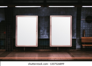 Two empty ad vertical posters templates on a metro platform; blank information banners placeholders indoors; a subway or a train station with two white billboards in front of a blue tile wall