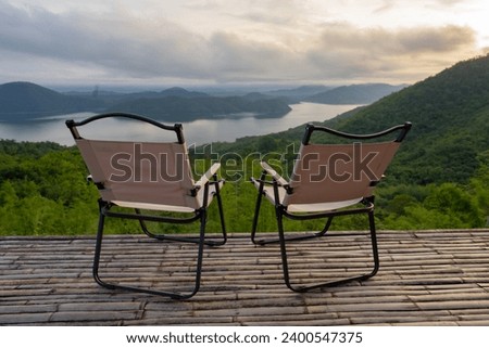Two Empty Camping Chairs Standing on the Top of the Mount. Perfect Place for Watching Sunset. Actice Relaxation Lifestyle, Tourist tent in camp among with mountain view on sunrise, Travel vacation.