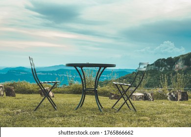 Two Empty Chairs Facing Each Other At The Top Of The Valley.  There's A Table Between Them.