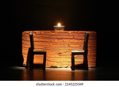 Two Empty Chairs Facing Each Other Near Candle Against Brick Background