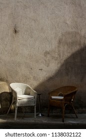 Two empty chairs on sidewalk in front of old buildings in France