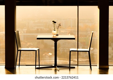 Two Empty Chairs And A Table With Föowers In Front Of A Sunset