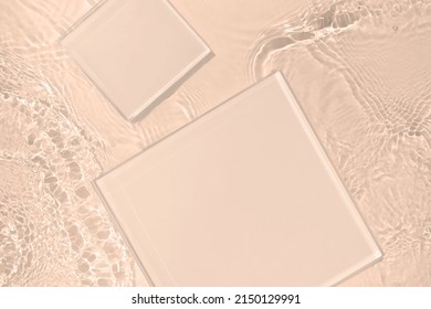 Two empty clear glass square podiums on beige transparent calm water texture with waves in sunlight. Abstract nature background for product presentation. Flat lay cosmetic mockup, copy space. - Shutterstock ID 2150129991