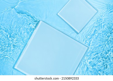 Two empty clear glass square podiums on blue transparent calm water texture with waves in sunlight. Abstract nature background for product presentation. Flat lay cosmetic mockup, copy space. - Shutterstock ID 2150892333