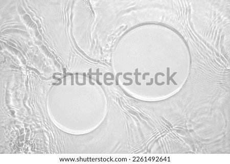 Two empty clear white circle podiums on transparent calm water texture with splashes and waves in sunlight. Abstract nature background for product presentation. Flat lay cosmetic mockup, copy space.
