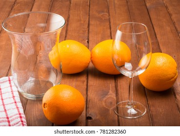 Two empty glasses and oranges on a wooden board