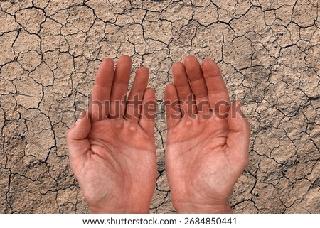 Two empty human hands held open against cracked dry soil. Concept of drought, climate change, poverty, need for water, hunger, and environmental crisis.