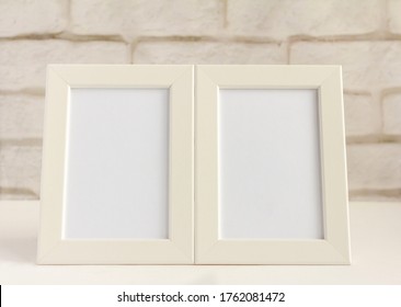 Two empty photo frames on a table or shelf with a copy of the space.