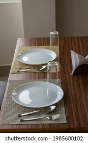 Two empty plates with spoon and fork on a wooden table with selective focus.