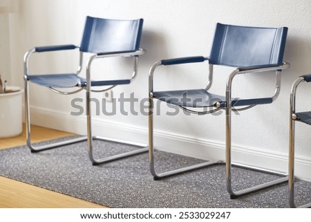 Two empty swing chairs stand in a doctor's waiting room and wait for patients, they stand on a carpet in front of a light wall