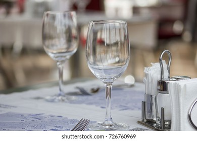 Two empty transparent wine glasses stand at table in small Japanese restaurant.