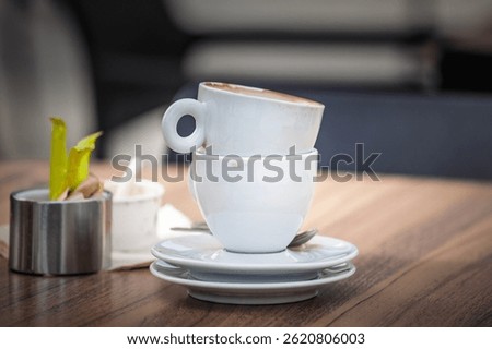 Two empty used espresso cups, coffee cups, stacked rim-to-rim on saucers with spoons rest on a wooden cafe table, illustrating break time after coffee.
