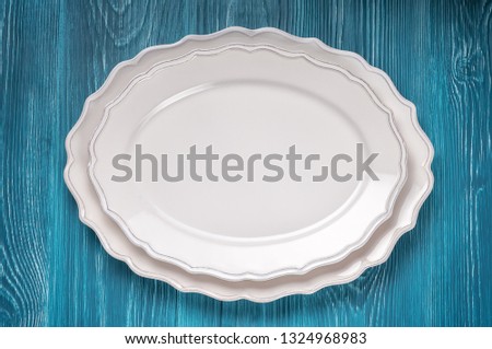 Two empty white serving dishes on a blue wooden background, top view. Can be used as a mock-up.