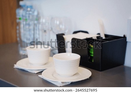 two empty white tea or coffee cups on a table in the hotel room. A set of dishes, kettle, coffee and tea for guests.