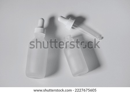 Two empty white translucent glass dropper vials, one bottle open. Flatlay on white background. Horizontal beauty and lifestyle background, mockup, and copy space. Professional lighting.