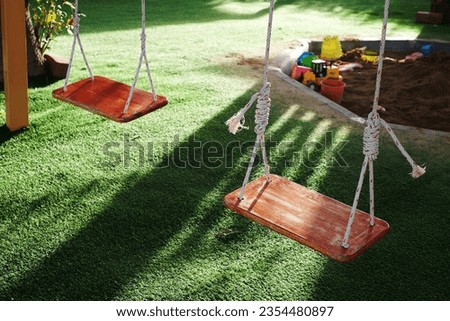 Two empty wooden swing with sunlight in playground.