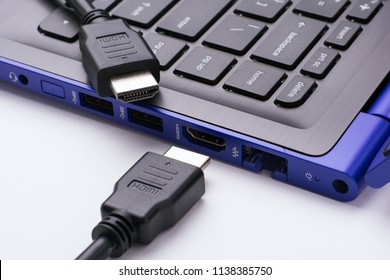 Two ends of the HDMI cable near the HDMI port of the modern blue laptop on a white background