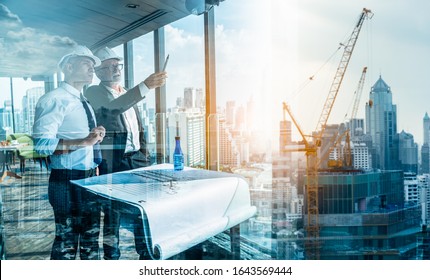 Two Engineer or Architect are analyzing blueprints while working on a new project on construction site with blue sky and city background.Architect supervising construction on terrace tower. - Shutterstock ID 1643569444