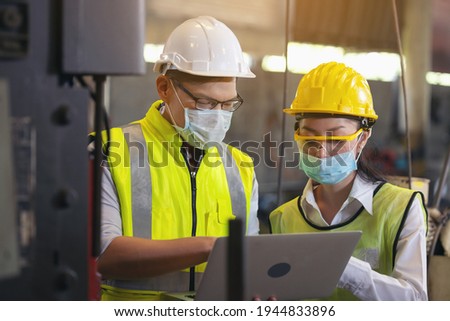 Two engineer in hard hat wearing safety using laptop for planning a project. Foreman explaining machinery to female employee
