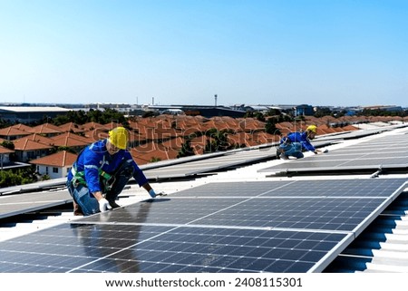 Two engineer men installing solar panels on factory roof, expert photovoltaic technicians working with ecologial renewable energy on high building rooftop